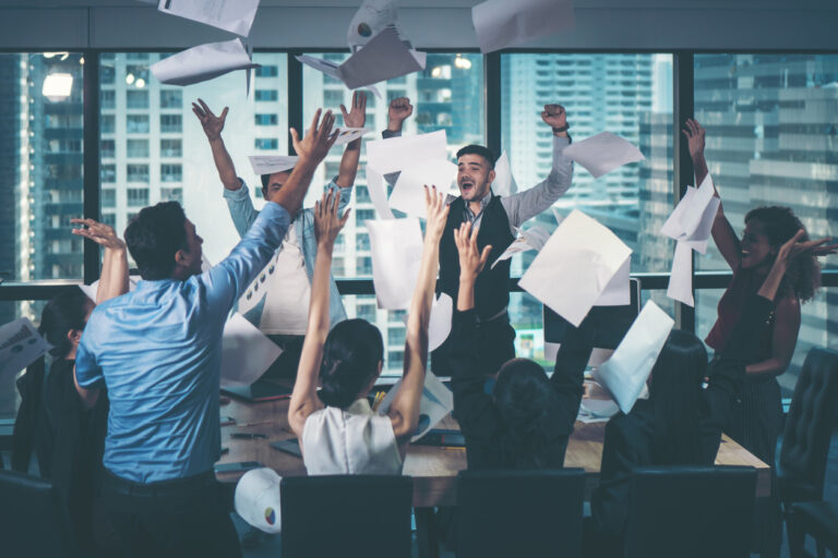 Group of business people celebrating by throwing their business papers in the air