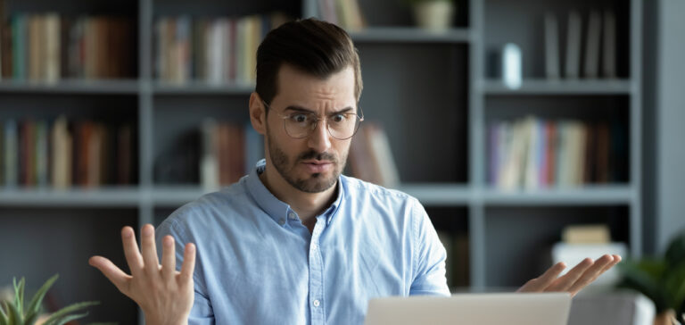 Unhappy young man work on laptop confused by gadget problems