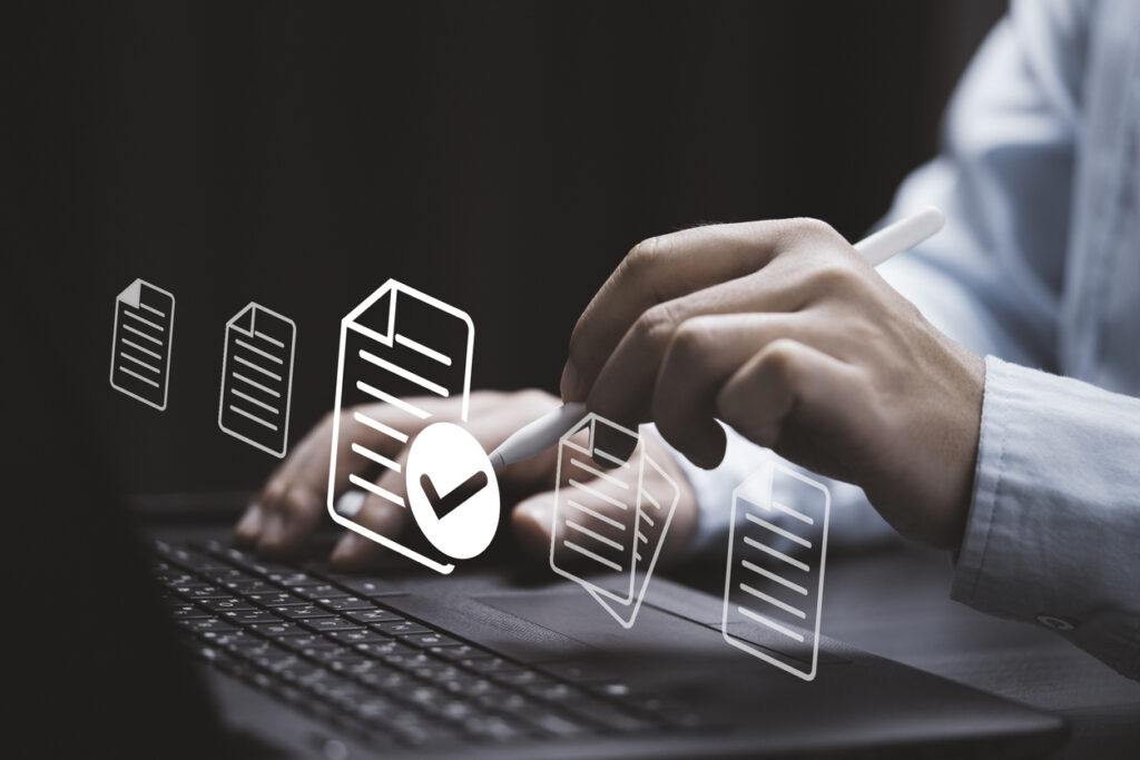 Businessman using laptop computer and electronic pen with virtual document and correct mark sign for online paperless approve project document and quality assurance concept.