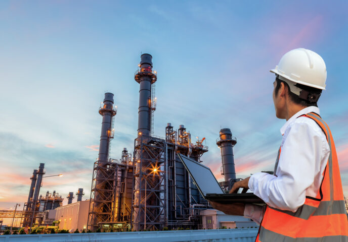 Engineering is use notebook check and standing in front of oil refinery building structure in heavy petrochemical industry